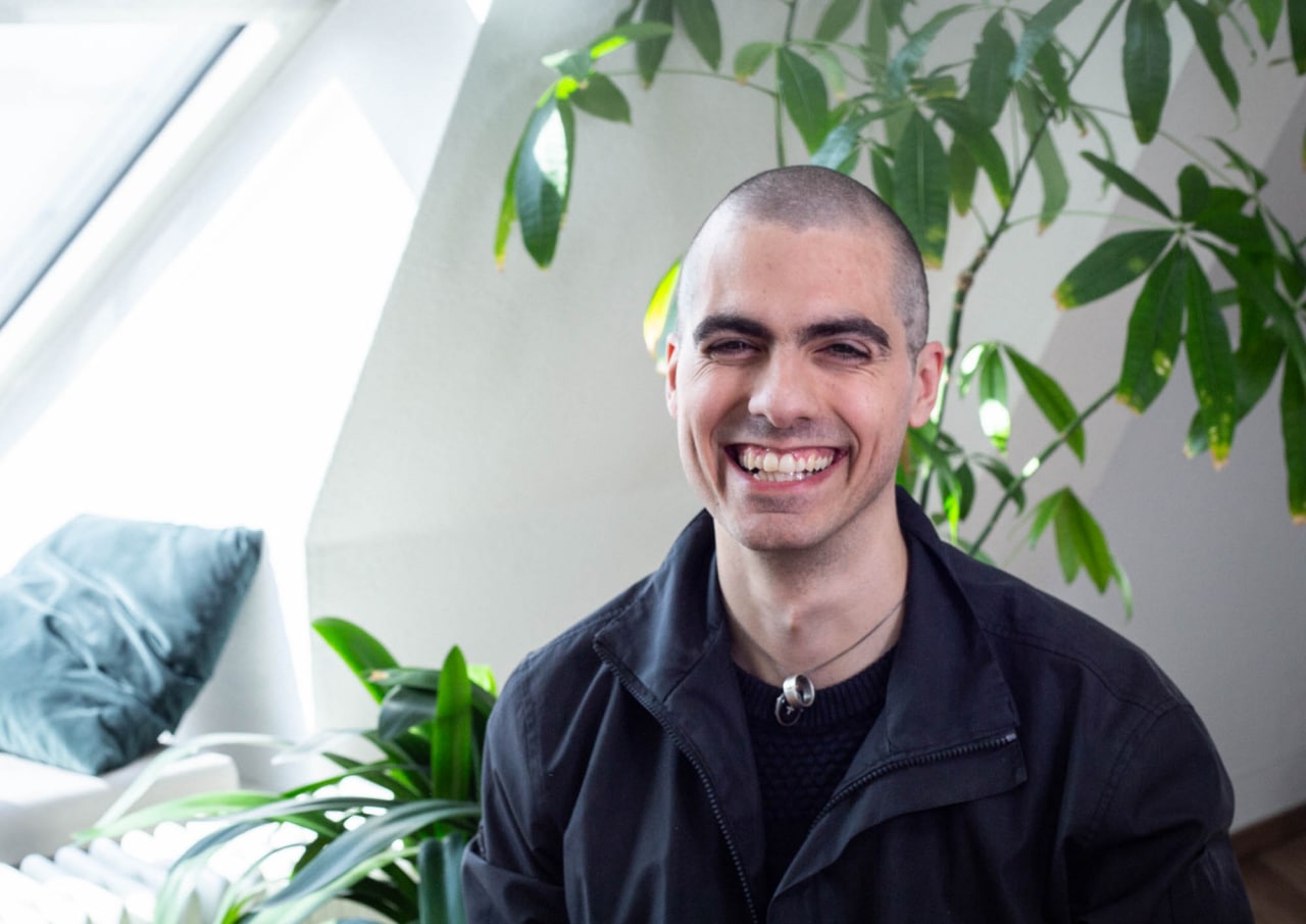 Tao Hansen smiling in a red plaid shirt and tortoise shell glasses